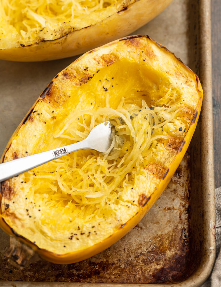 Overhead view of a grilled spaghetti squash half on a baking sheet.