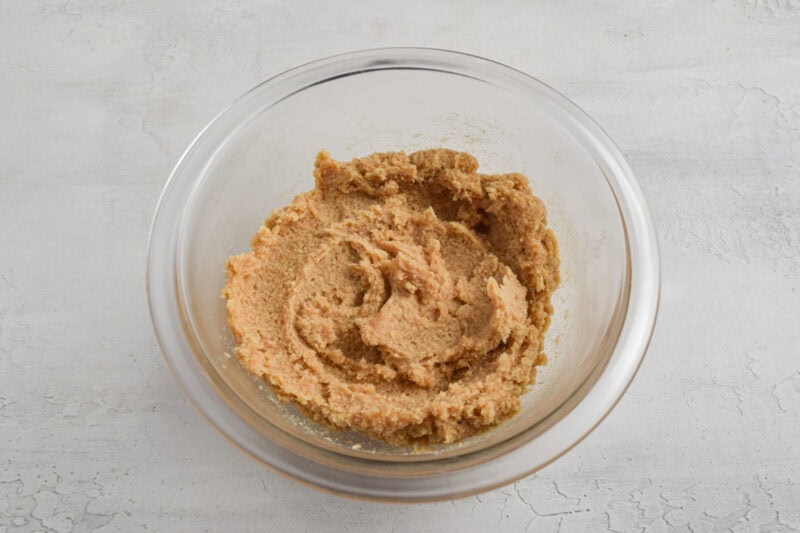 Keto cookie dough batter in a small glass mixing bowl on a white table.