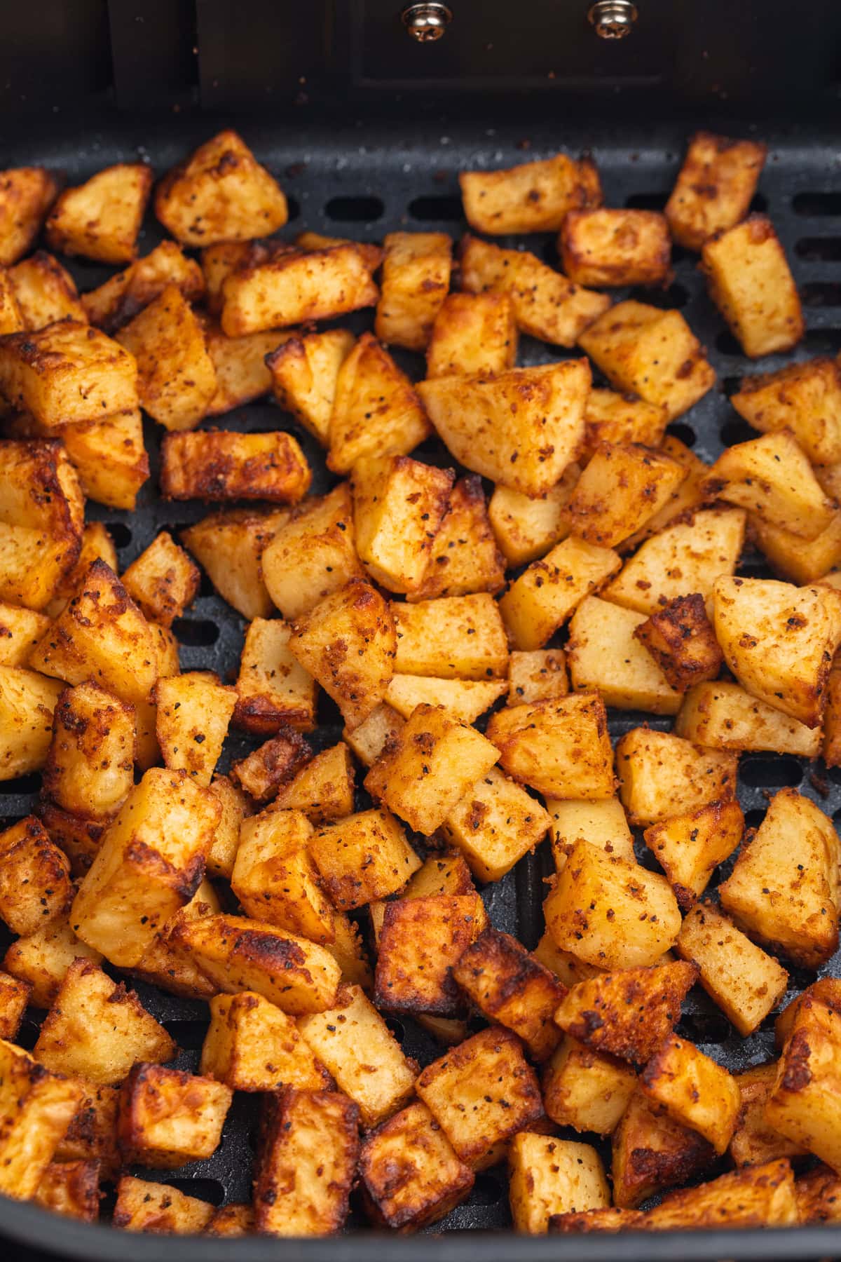 Overhead view of air fryer breakfast potatoes in an air fryer basket.