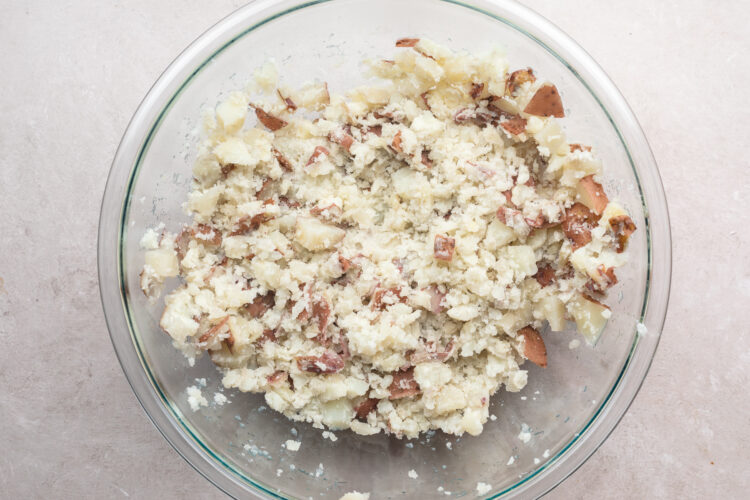 Overhead view of mashed red skin potatoes in a large glass mixing bowl.