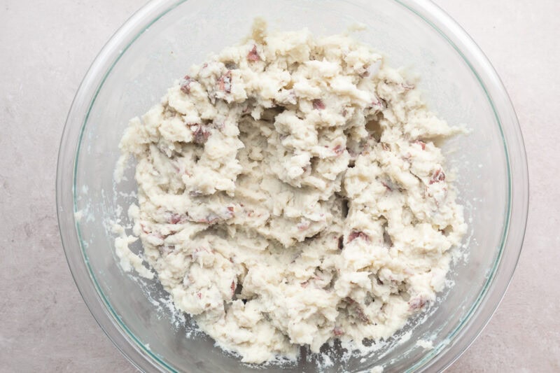 Overhead view of mashed red skin potatoes in a large glass mixing bowl.