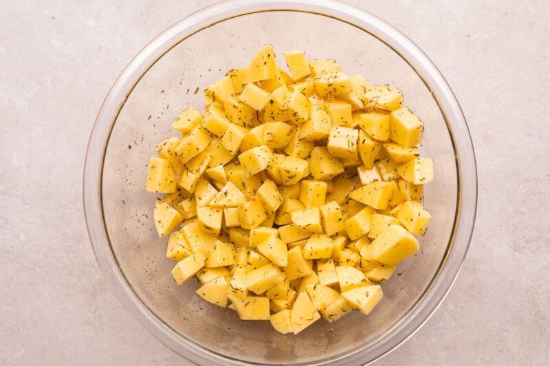 Overhead view of diced potatoes in a large glass mixing bowl.