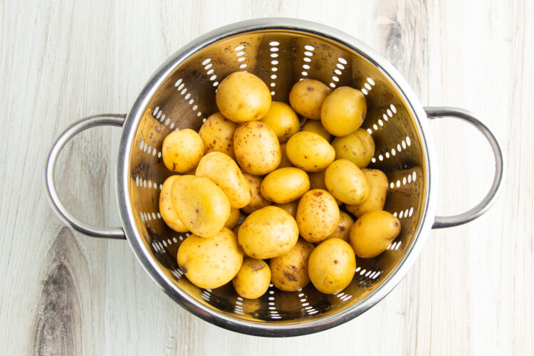 Overhead view of baby potatoes in a large colander.