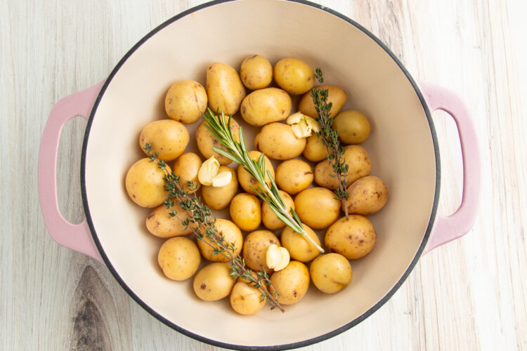 Baby potatoes in large baking dish with aromatics and garlic.