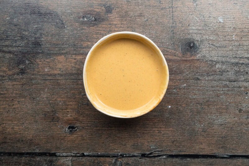 Overhead view of prepared keto Chick-fil-A sauce in a small bowl on a wooden table.