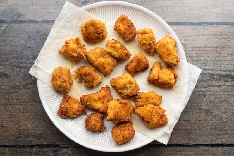Overhead view of fried keto chicken nuggets on a plate lined with paper towels.