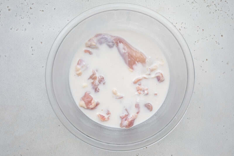 Chicken submerged in a buttermilk mixture.
