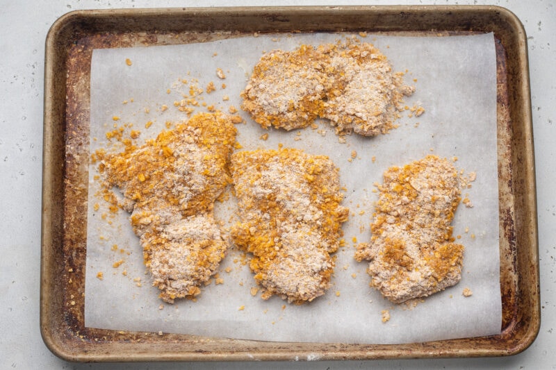 Breaded hot honey chicken on a baking sheet lined with parchment paper.