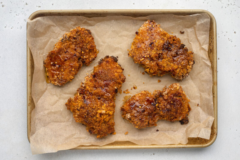 Hot honey chicken on a baking sheet lined with parchment paper.