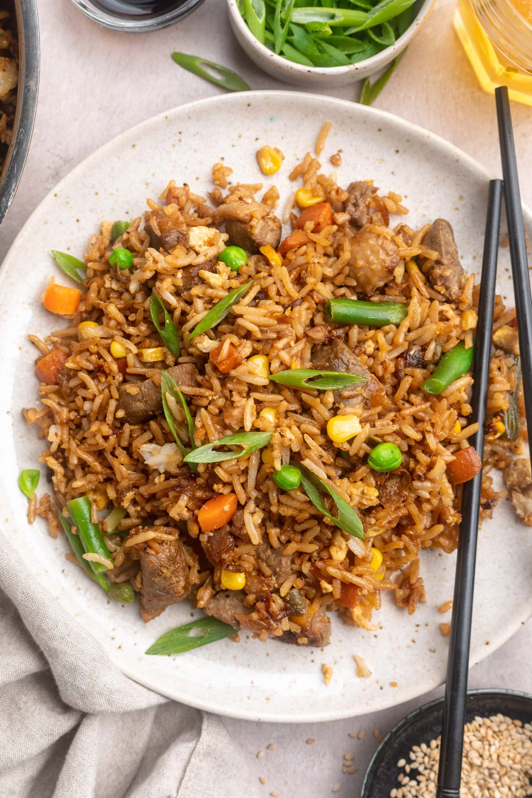Overhead view of a large white plate of duck fried rice with veggies.