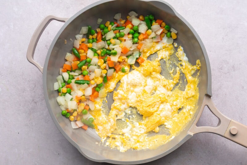 Mixed veggies and scrambled eggs in a large skillet.