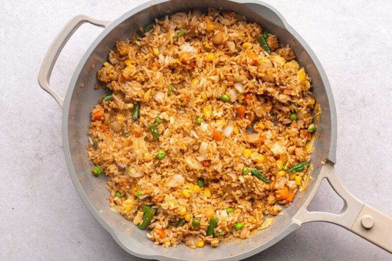 Fried rice, soy sauce, veggies, and eggs in large skillet.