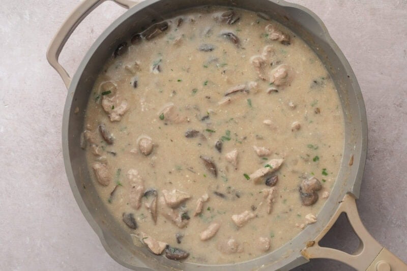 Overhead view of prepared pork stroganoff in a large skillet.