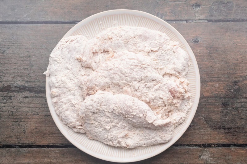 Breaded chicken breasts on a round white plate.