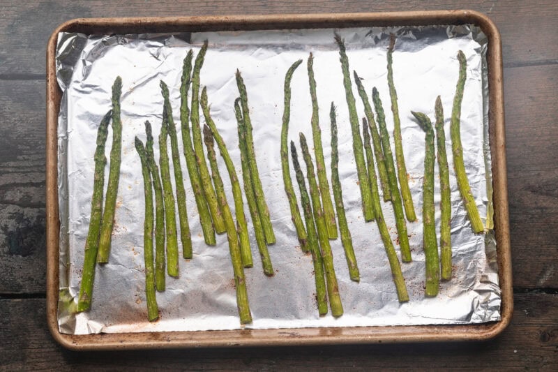 Asparagus spears on baking sheet lined with aluminum foil.