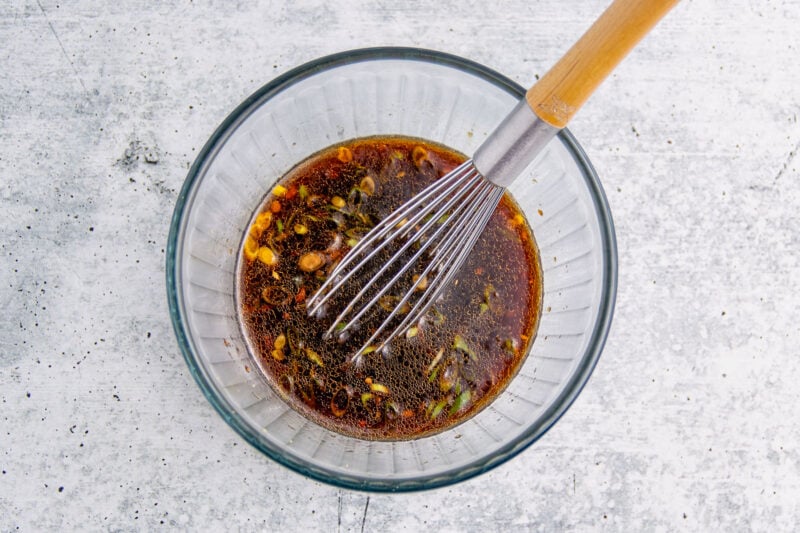 Air fryer tuna steak marinade in a glass mixing bowl with a whisk.