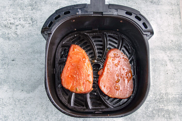 Ahi tuna steaks in an air fryer basket.