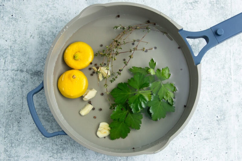 Aromatics for poached shrimp in a large pot.