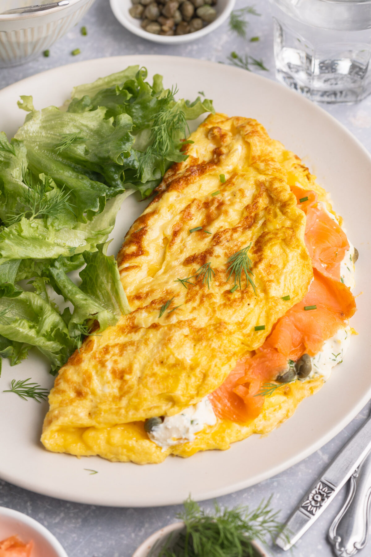 Overhead view of a folded salmon omelette on a plate with a green salad.