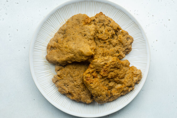 Vegan chicken fillets made from seitan and boiled in vegetable broth, resting on a plate.
