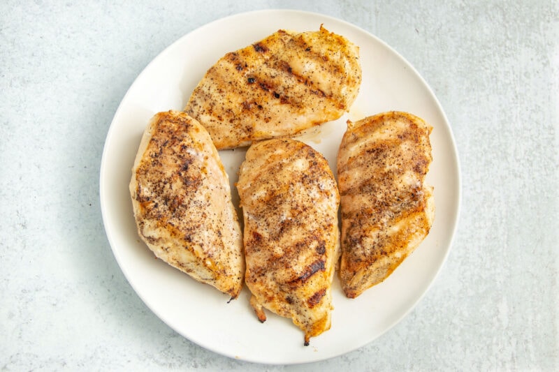 Grilled chicken breasts on a round white plate.