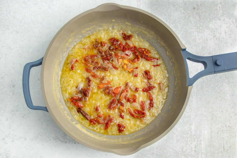 Melted butter with sun-dried tomatoes in a large skillet.