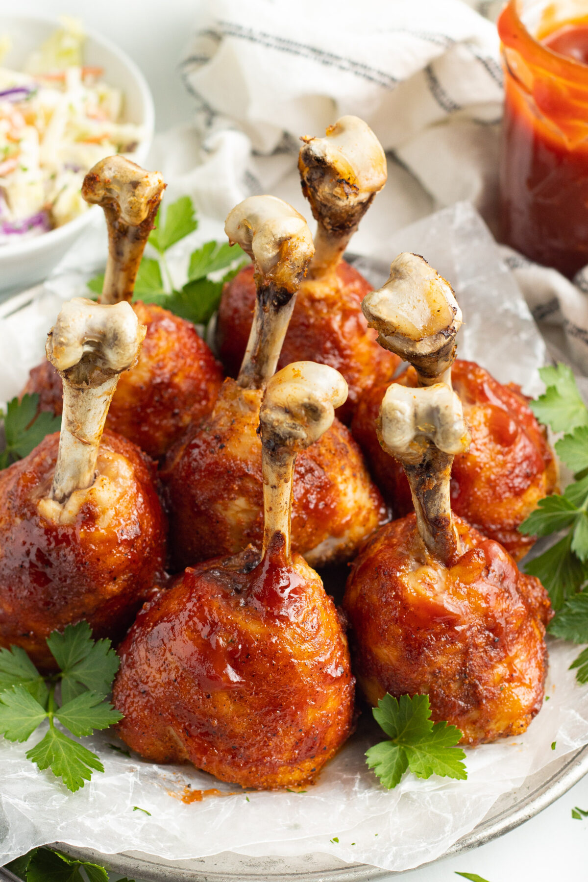 Overhead, angled view of lollipop chicken legs standing upright on a plate.