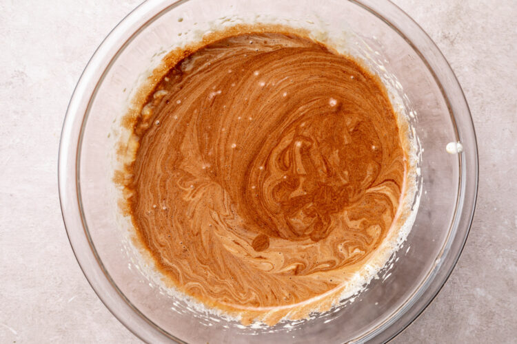 Melted chocolate added to sugar and egg mixture in large glass mixing bowl.