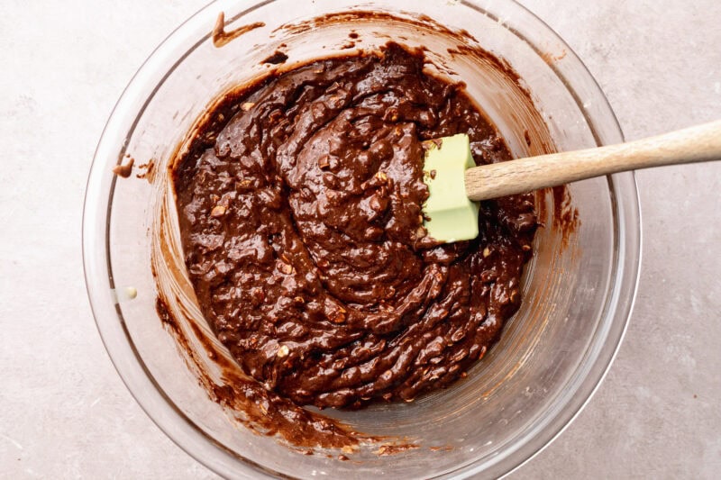 Prepared lactation brownie batter in a large glass mixing bowl with a silicone spatula.