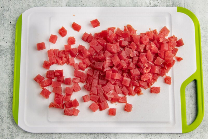 Chunks of ahi tuna on a plastic cutting board with lime green edges.