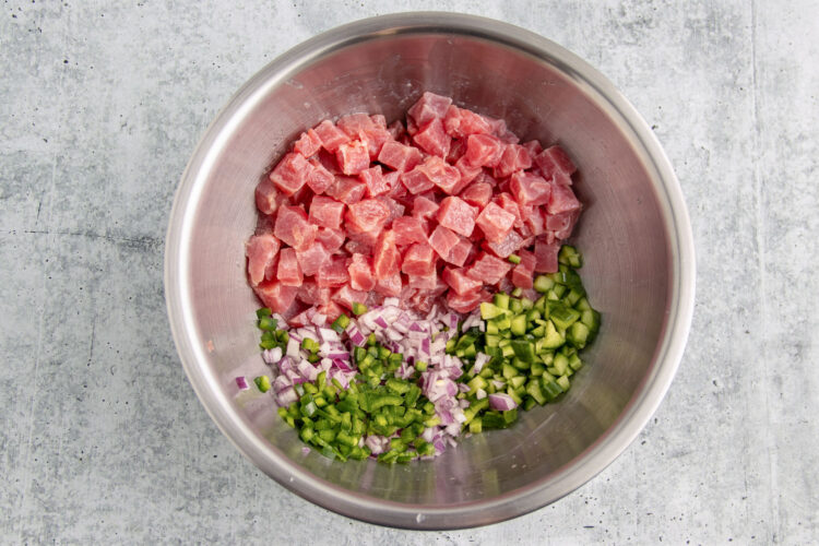 Ingredients for tuna ceviche in a large silver mixing bowl.