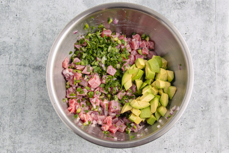 Ingredients for tuna ceviche in a large silver mixing bowl.