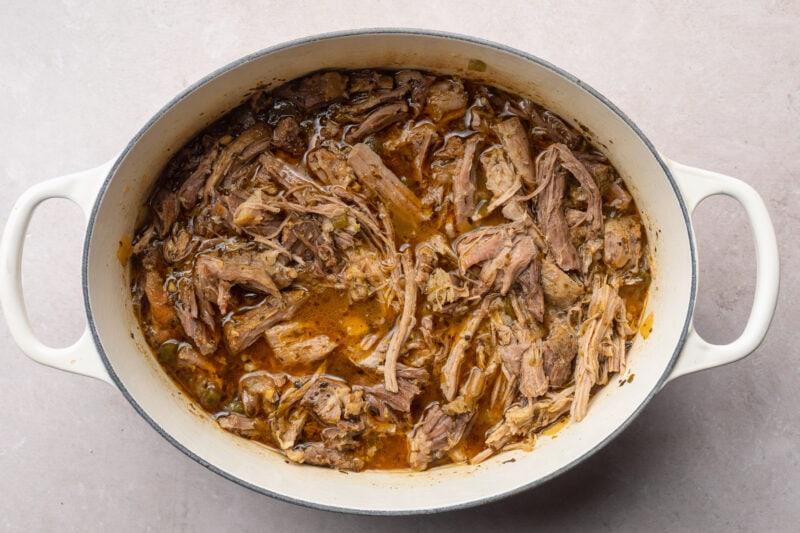 Shredded pork carnitas in a large dutch oven.