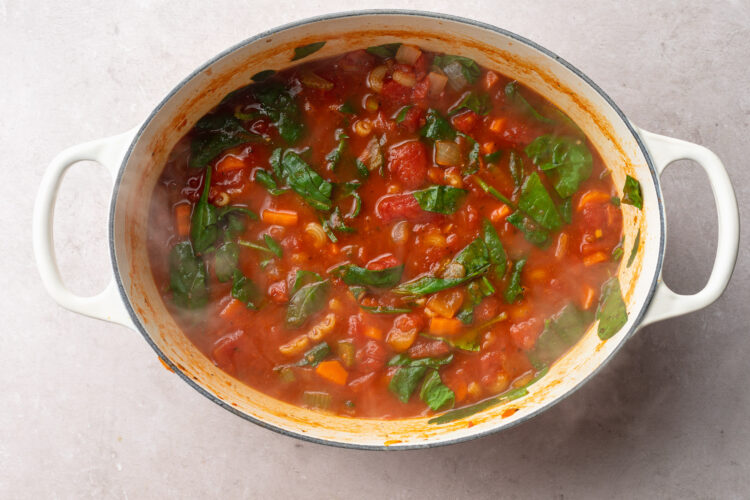 Top-down view of tomato florentine soup in a large oval stockpot.