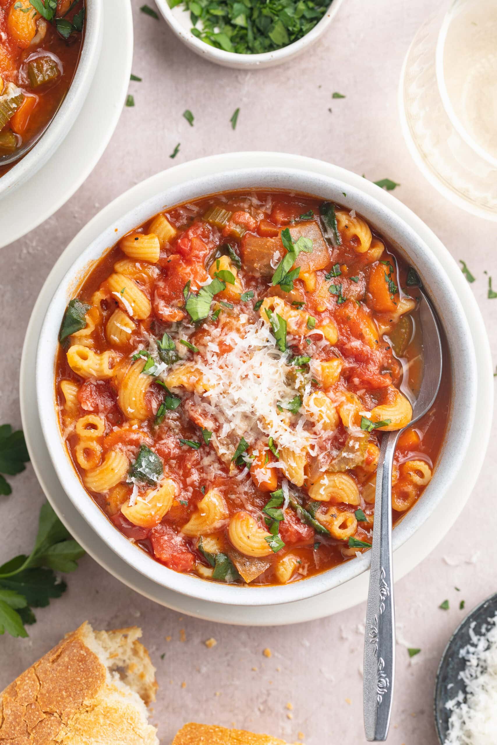 A white bowl of tomato florentine soup on a white tabletop.