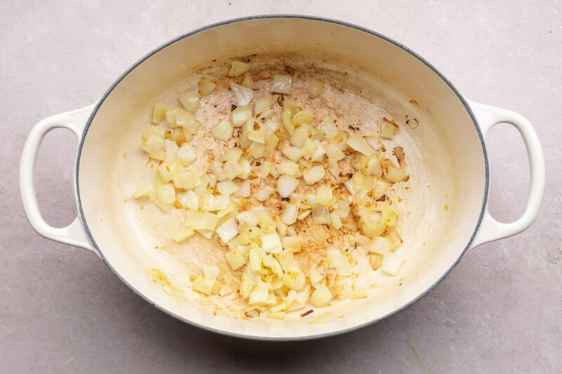 Diced onion and garlic in a large oval dutch oven with 2 handles.