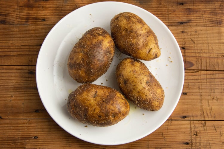 Oiled and seasoned potatoes resting on a plate.