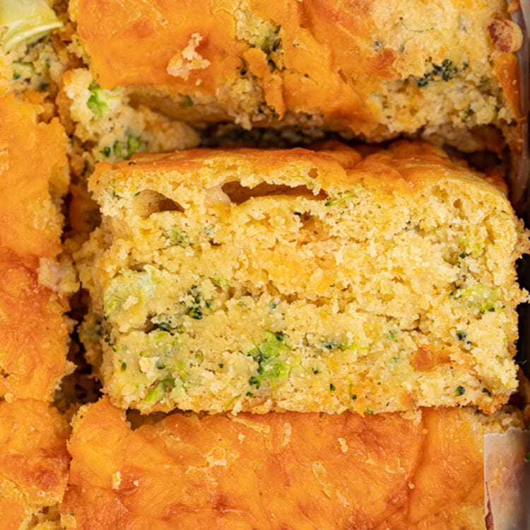 A square of broccoli cornbread turned on its side to show the cross section.