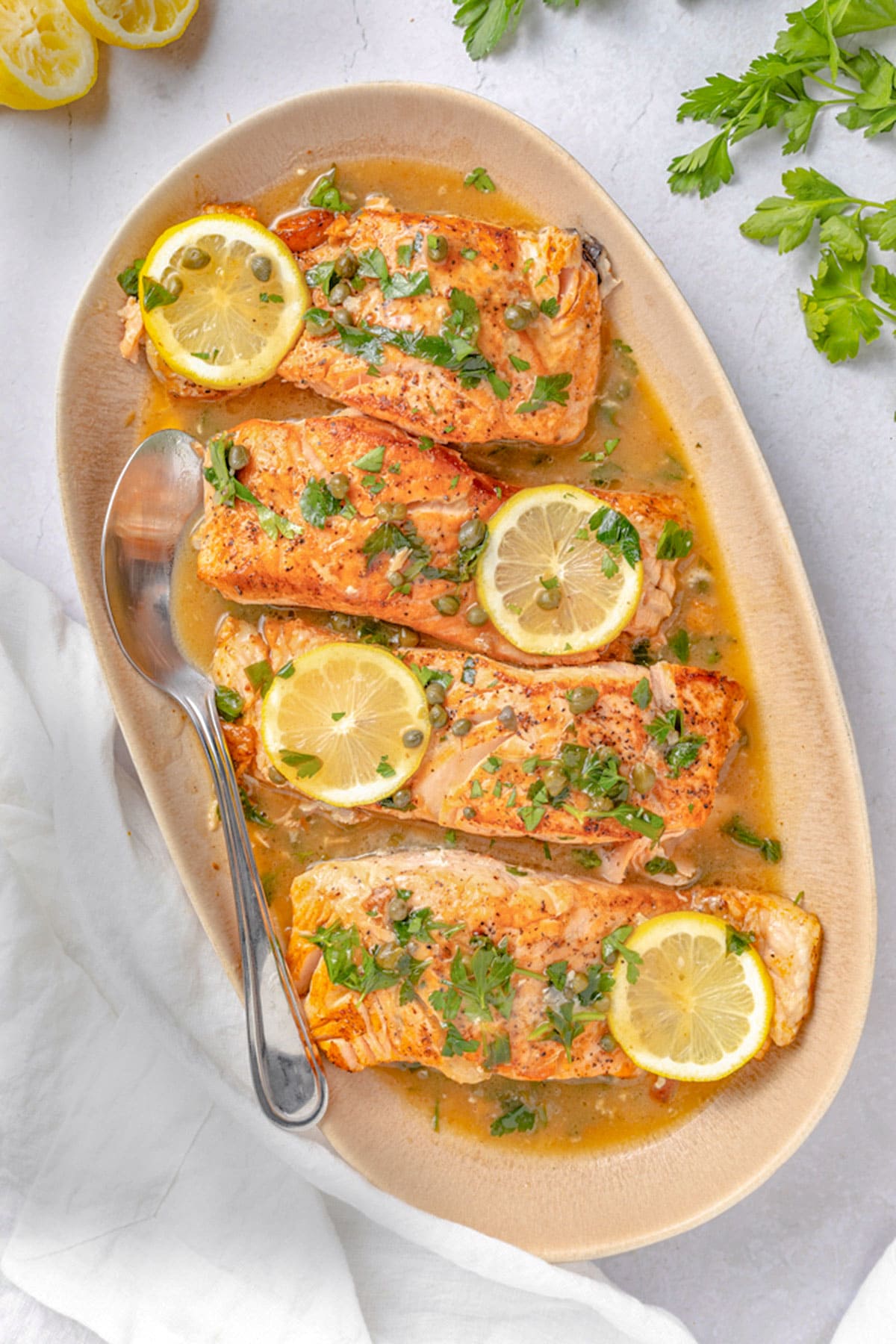 4 salmon piccata fillets on an oval serving platter.
