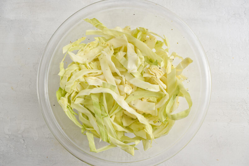 Simple homemade slaw with shredded cabbage in a medium glass mixing bowl.
