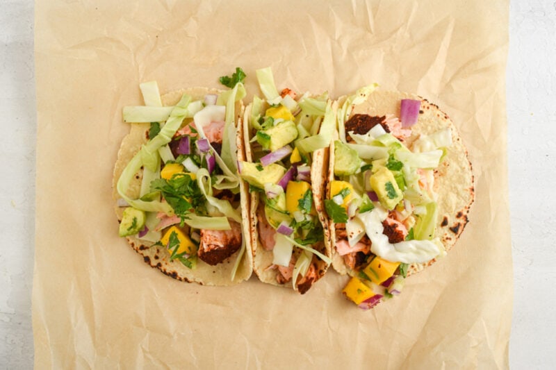 Assembled salmon tacos on a sheet of parchment paper.