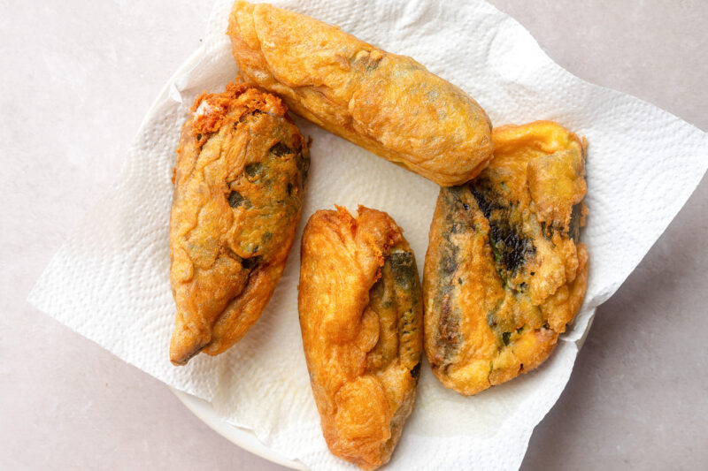 Fried peppers on a large white plate with paper towels.
