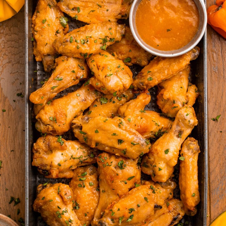 A pan of juicy chicken wings in an orange mango habanero sauce.