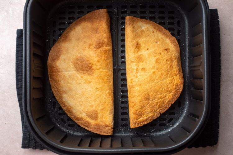 Two golden, crispy quesadillas in an air fryer basket.