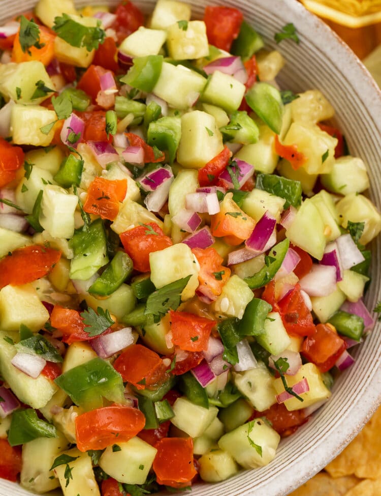 Close-up overhead shot of cucumber salsa with tomato and onion in a large bowl.