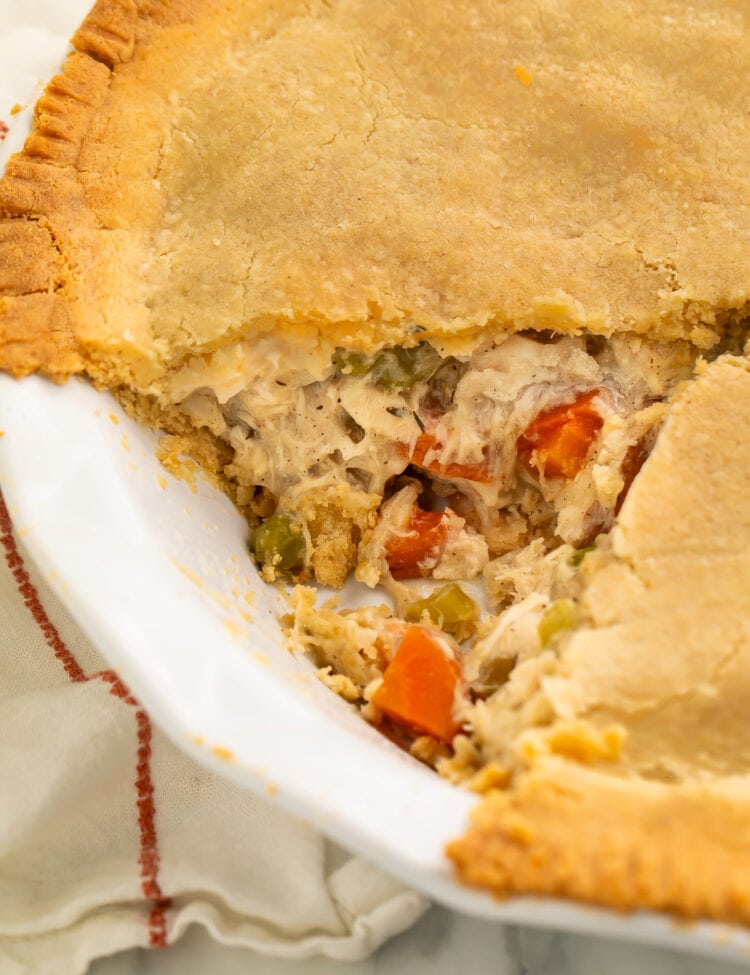 A close-up look at a gluten free chicken pot pie with a triangular slice of pie taken out of the pie plate.