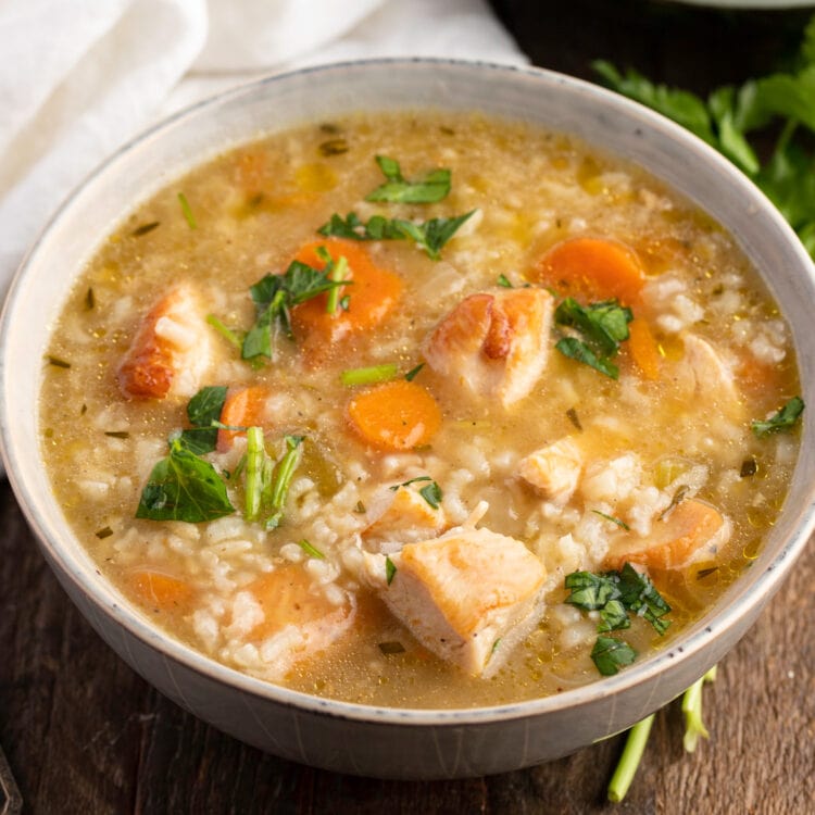 A soup bowl holding nutritious, cozy, loaded chicken and rice soup with veggies.