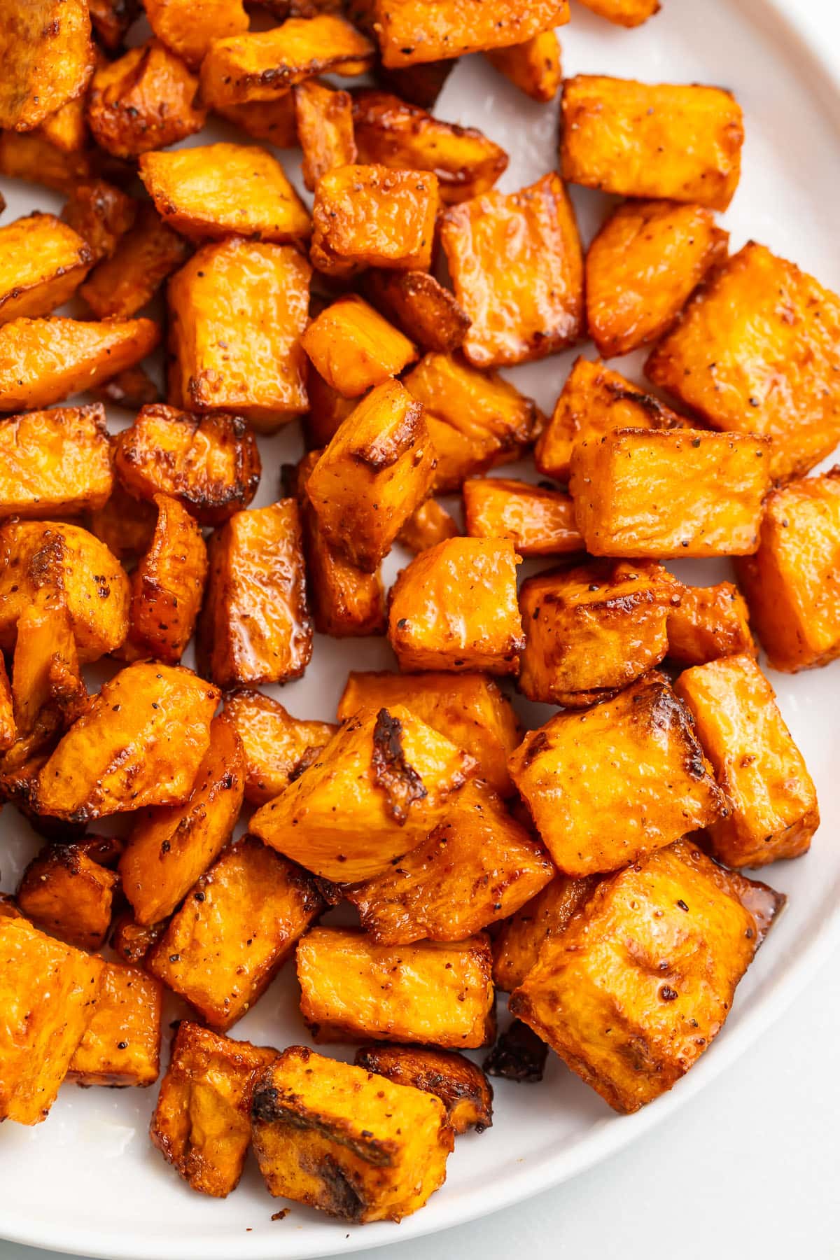 Sweet potato cubes, cooked in the air fryer, shown on a white plate.