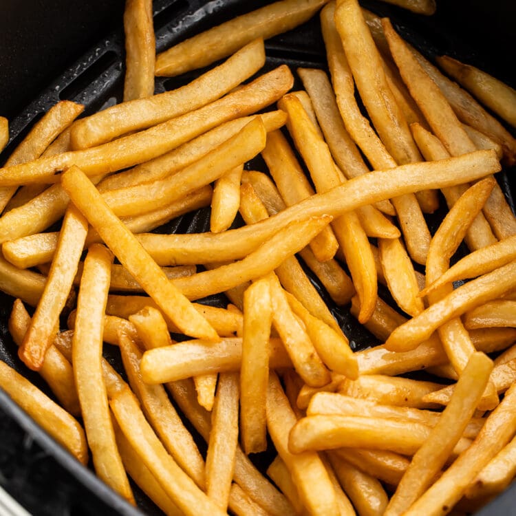 Reheated french fries in an air fryer basket.