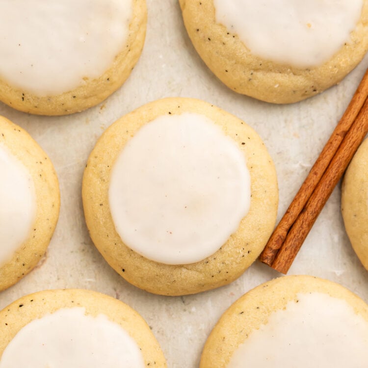 Close-up of a chai cookie made from Taylor Swift's recipe surrounded by other cookies flat on parchment paper, next to a cinnamon stick.